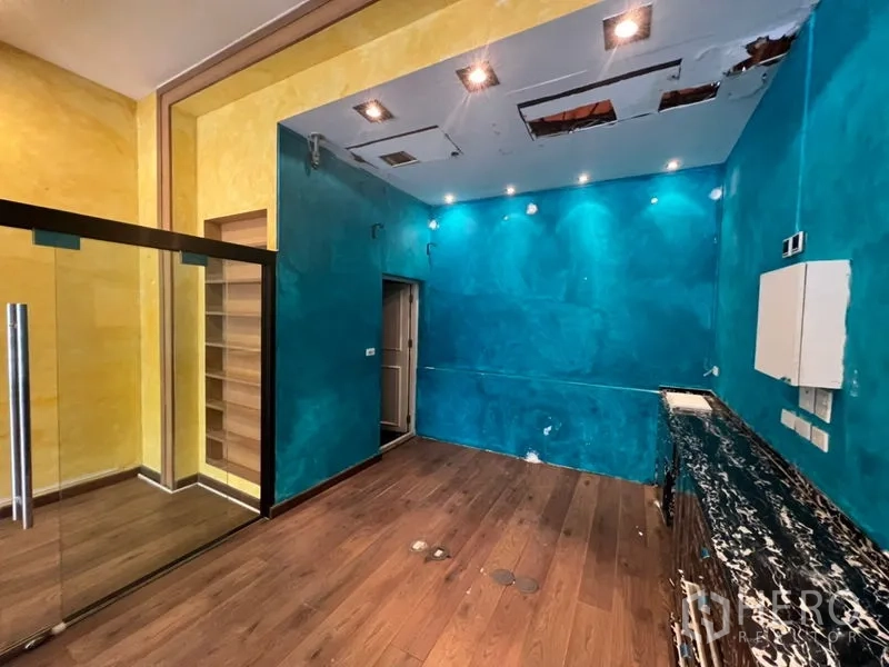 零售空间 出租在Watthana, Bangkok - 后场工作区，蓝色墙面、木地板、操作台与检修天花。