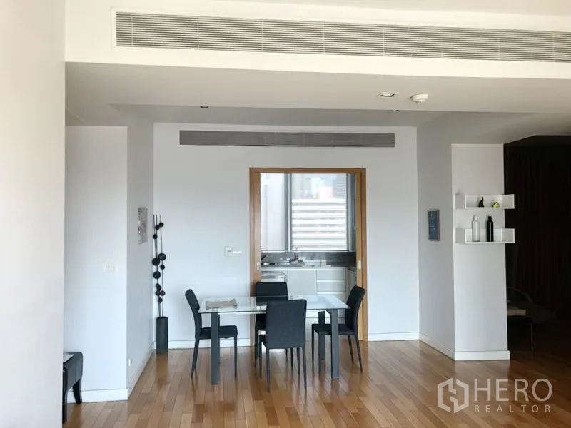 公寓 出租在Khlong Toei, Bangkok - 用餐区设四人玻璃餐桌与木地板，并有通往厨房的门。