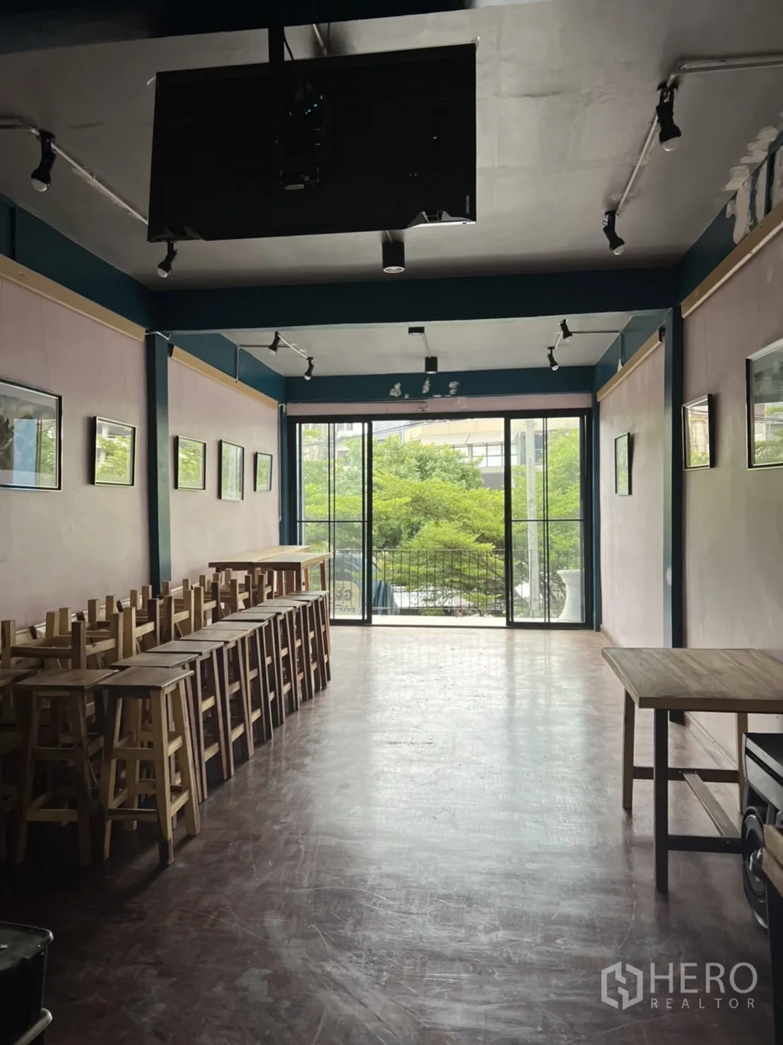อาคารพาณิชย์ ให้เช่าในWatthana, Bangkok - ชั้นบนแบบเปิดโล่ง มีไฟราง เก้าอี้ไม้เรียง และประตูกระจกบานเลื่อนไปยังระเบียงวิวต้นไม้