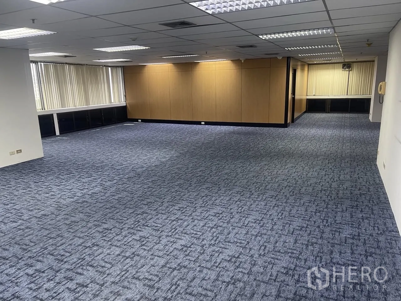Office Space for rent in Khlong Toei, Bangkok - Expansive open office with carpet tiles, wood partitions, and a long band of windows.