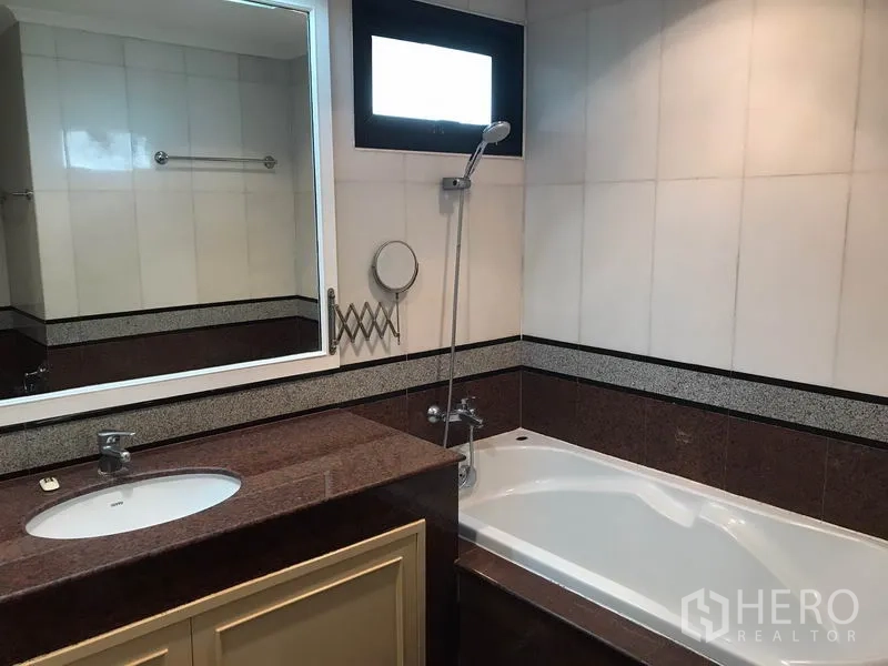 Condominium for rent in Sathon, Bangkok - Bathroom with bathtub, handheld shower and long vanity under a mirror.