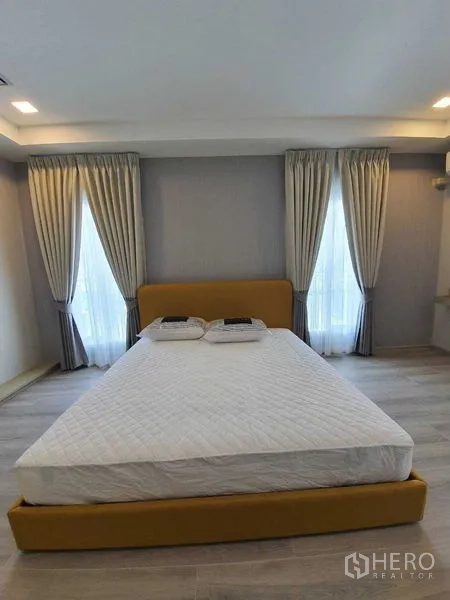 Townhouse for rent - Master bedroom with double bed, tall curtained windows, and soft lighting.