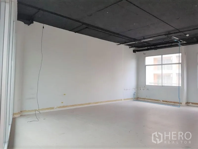 办公空间 出租在Phra Khanong, Bangkok - 未配家具的开放式办公室，黑色外露天花、白墙与大窗户，采光充足。