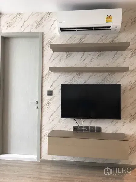 Condominium for rent in Watthana, Bangkok - Feature wall with mounted TV, floating shelves and an air conditioner above.