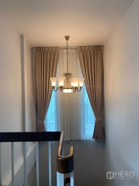 Detached House for rent in Ratchathewi, Bangkok - Stairwell with a chandelier and tall curtained window.