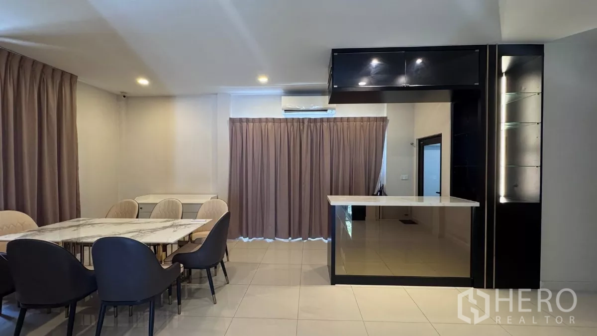 บ้าน ให้เช่าหรือขายในSaphan Sung, Bangkok - มุมรับประทานอาหารพร้อมโต๊ะหินอ่อนและเคาน์เตอร์บาร์ มีตู้แขวนและผ้าม่านปิดหน้าต่าง.