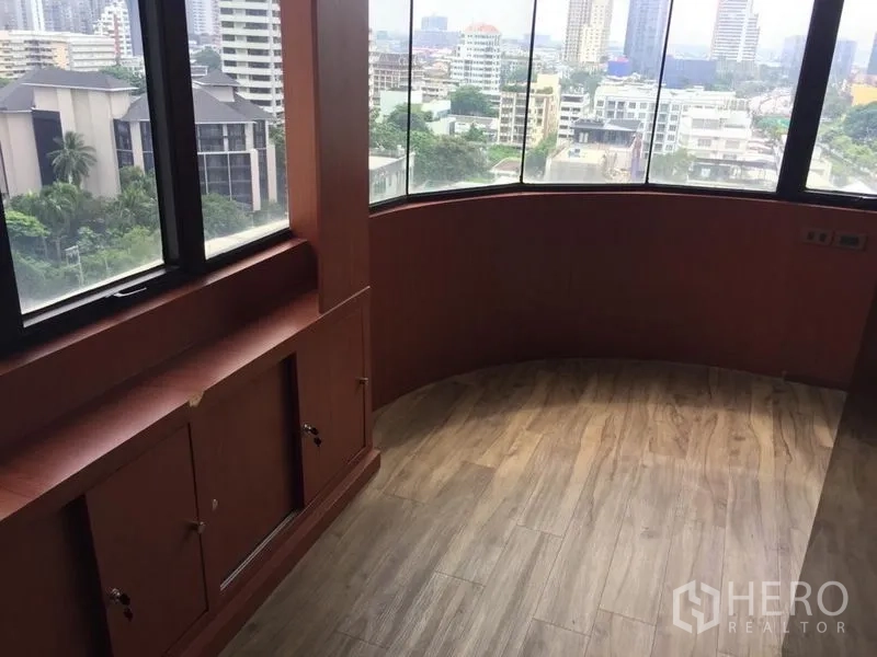 Office Space for sale in Watthana, Bangkok - Curved corner workspace with built-in cabinets and floor-to-ceiling windows facing the city.