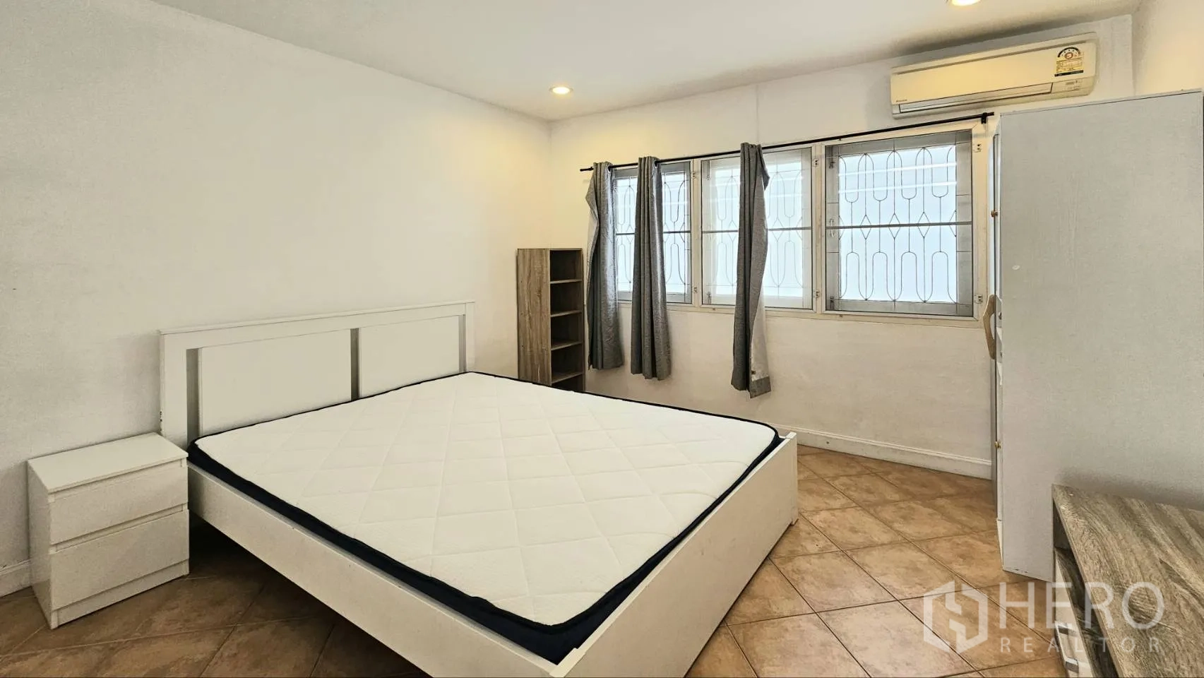 Detached House for rent in Saphan Sung, Bangkok - Spacious bedroom with double bed, three windows, air conditioner, and neutral curtains.