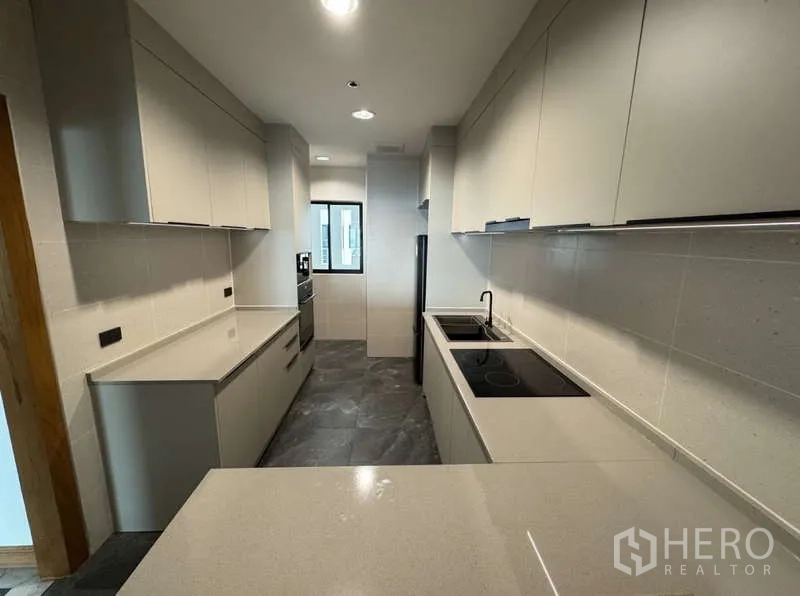 คอนโด ให้เช่า - มุมครัวอีกด้าน แสดงอ่างล้างจานคู่ เตาอบ และท็อปครัวยาว