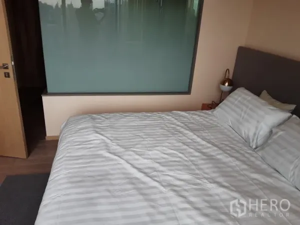 公寓 出租或出售在Watthana, Bangkok - 温馨卧室一角，双人床、床头灯与磨砂玻璃隔断。