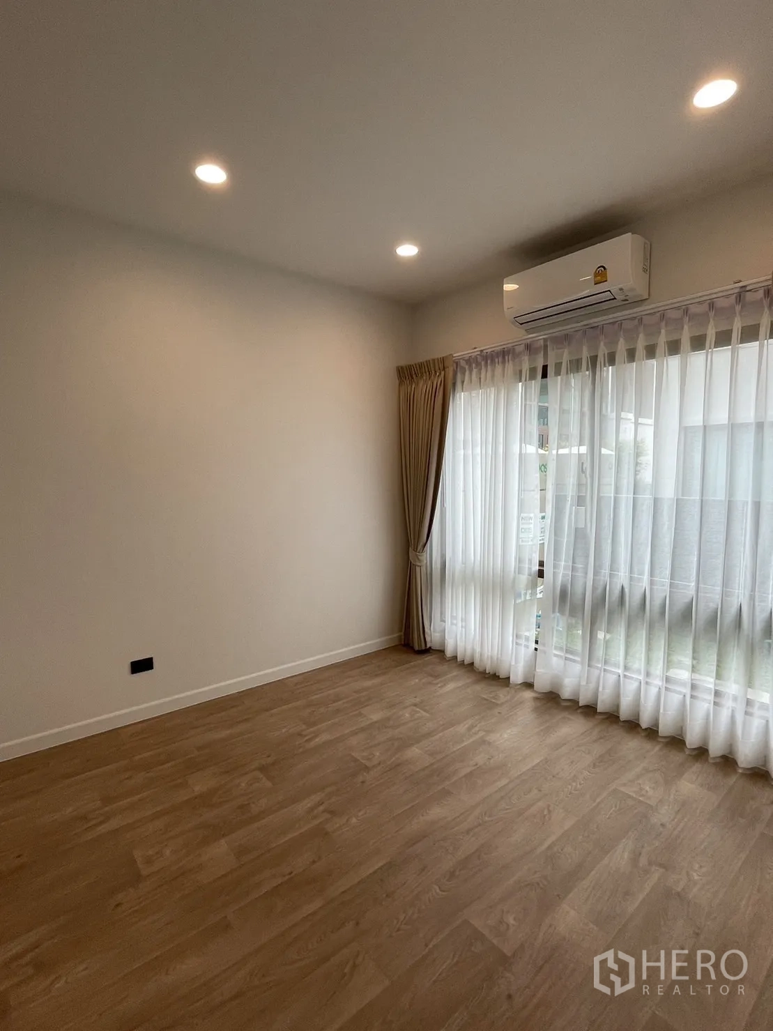 Detached House for rent in Bang Kapi, Bangkok - Empty multipurpose room with wood flooring, air conditioning, and sheer curtains.