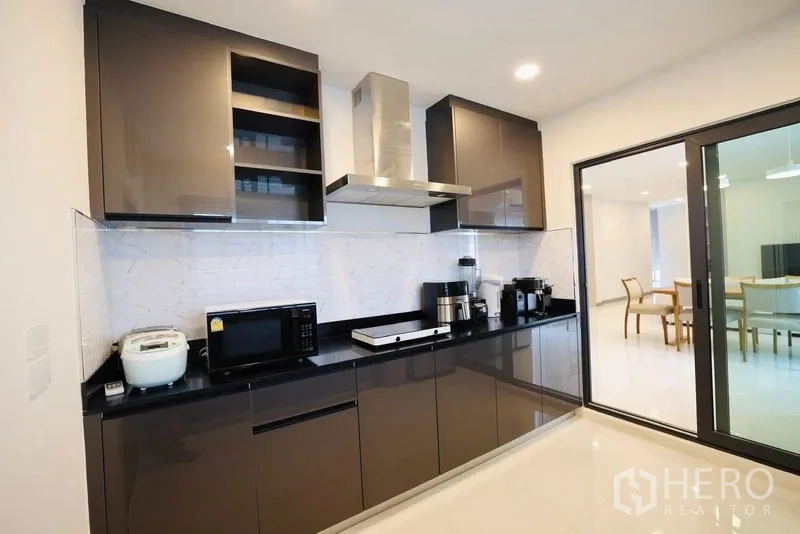 Detached House for rent in Bang Phli, Samut Prakan - Modern kitchen with glossy cabinets, range hood, and small appliances.
