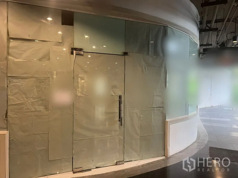 零售空间 出租在Watthana, Bangkok - 面向走道的弧形玻璃转角店面，上方配有射灯天花。