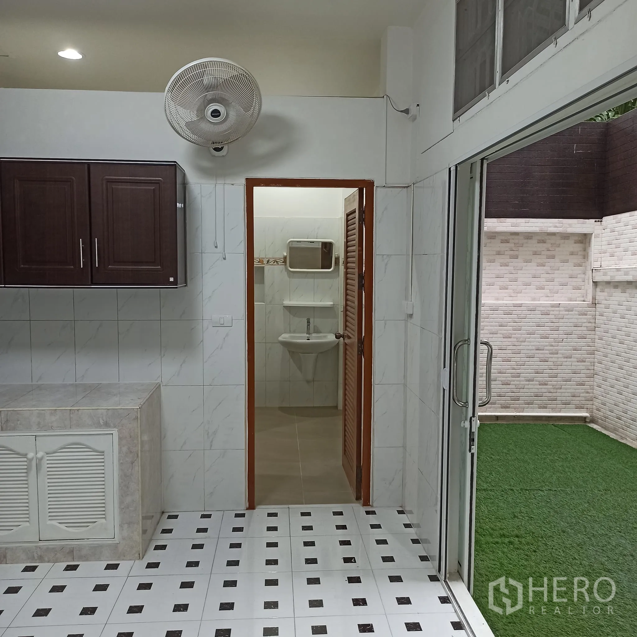Townhouse for rent in Wang Thonglang, Bangkok - Kitchen opening to a guest bathroom and grass courtyard.
