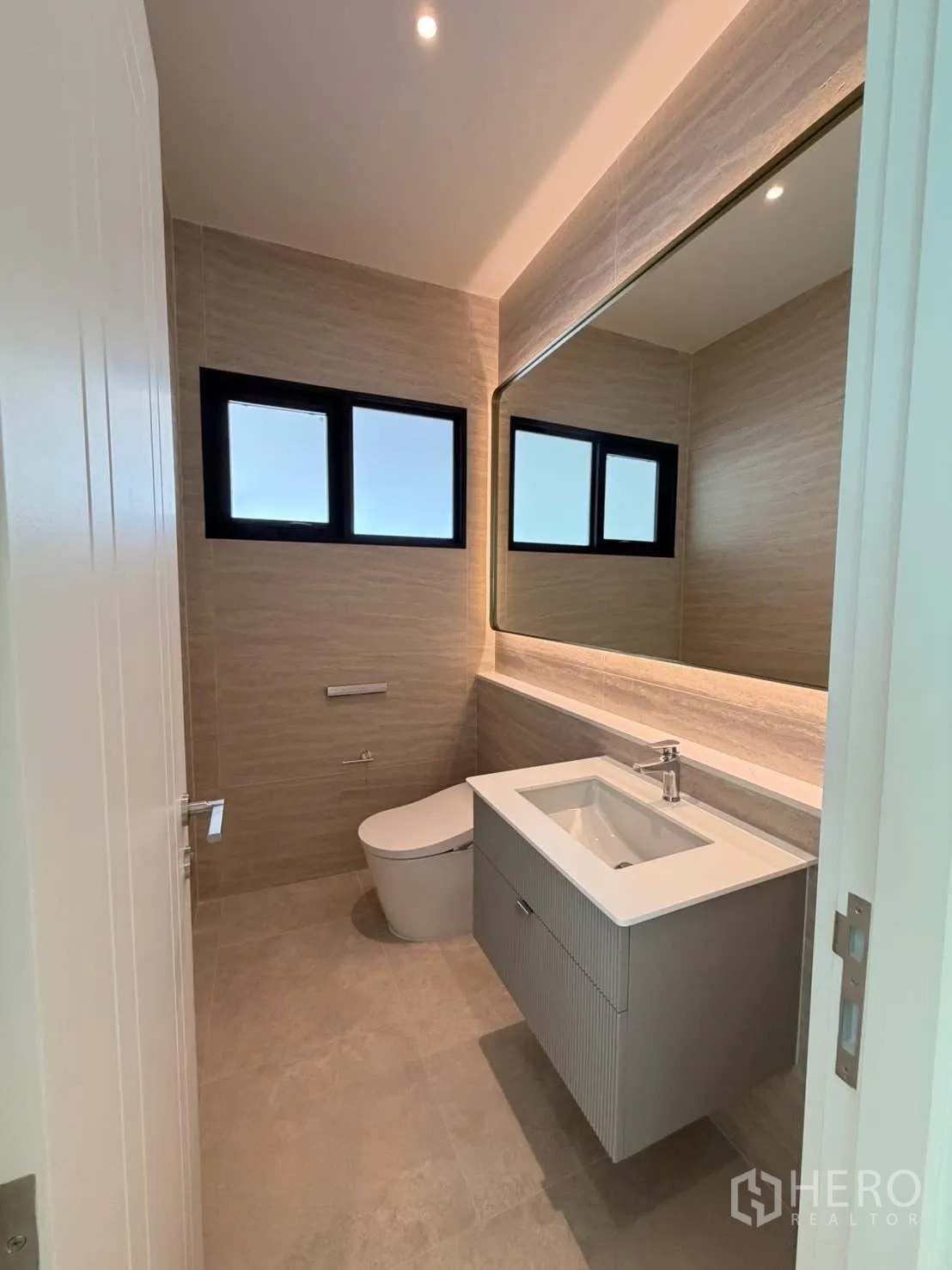 Detached House for rent in Saphan Sung, Bangkok - Powder room with wall-hung vanity, large mirror, and window.
