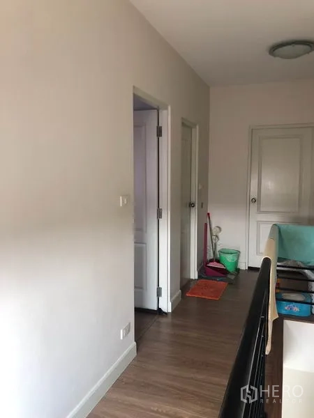 Townhouse for sale in Phasi Charoen, Bangkok - Upper-floor hallway with wood laminate flooring and white doors.