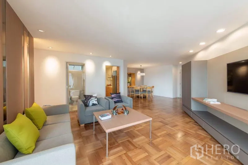 Apartment for rent - Bright living room with sofa set, TV wall, wood flooring and view toward the dining zone and bathroom.