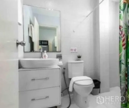 ทาวน์เฮาส์ ให้เช่าในKhlong Toei, Bangkok - ห้องน้ำโทนขาว อ่างล้างหน้า กระจก โถสุขภัณฑ์ และม่านอาบน้ำลายสีสัน