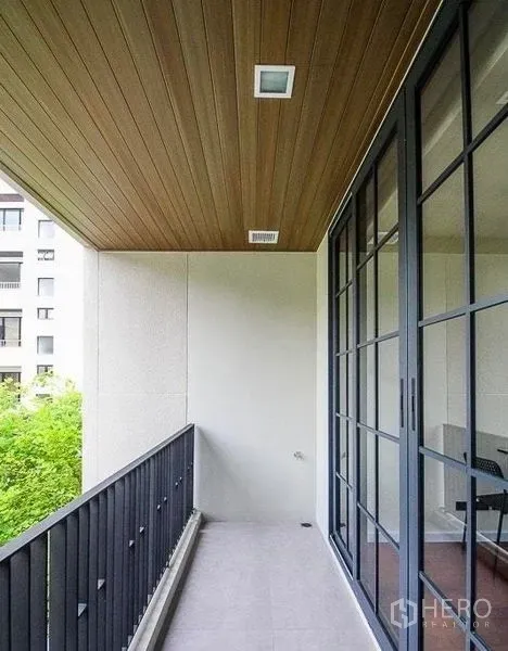 ทาวน์เฮาส์ ให้เช่าในWatthana, Bangkok - ระเบียงมีหลังคา ฝ้าไม้ ราวเหล็ก และประตูกระจก มองเห็นต้นไม้