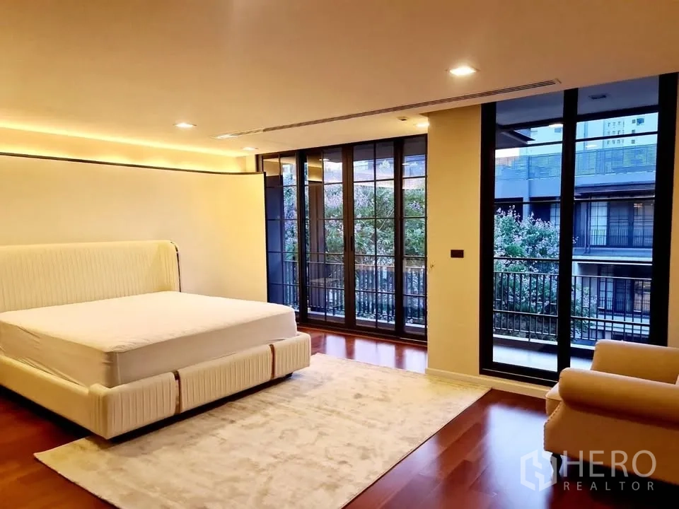 Townhouse for rent or sale in Watthana, Bangkok - Spacious bedroom with wall-to-wall windows and balcony views.