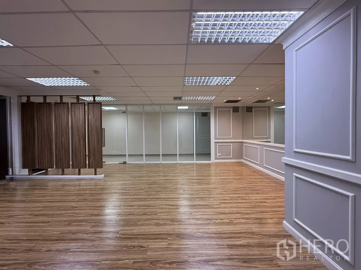 Office Space for rent - Open-plan office area with glass partition wall and wood slat divider under fluorescent lighting.