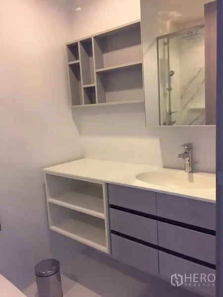 Condominium for rent in Watthana, Bangkok - Modern bathroom with built‑in vanity, open shelves, and a glass shower enclosure.
