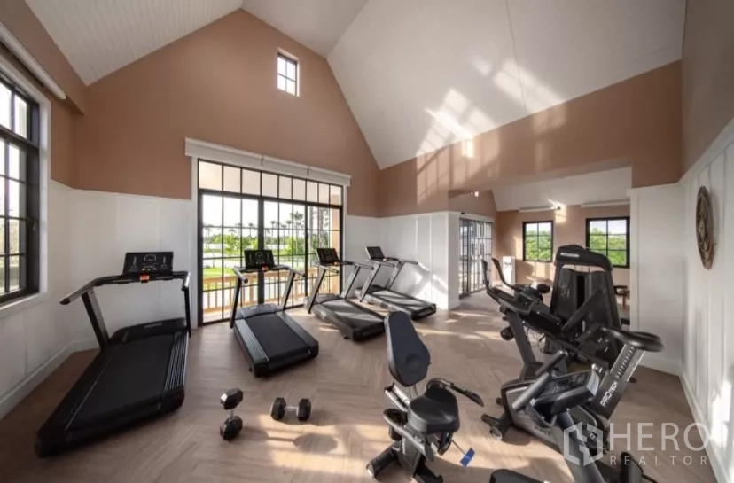 Townhouse for rent in Bang Phli, Samut Prakan - Fitness room with treadmills and exercise bikes overlooking garden views.
