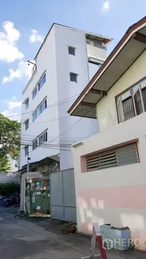 店屋 出租 - 街景视角的多层商铺楼立面与金属大门（帕卡侬）。