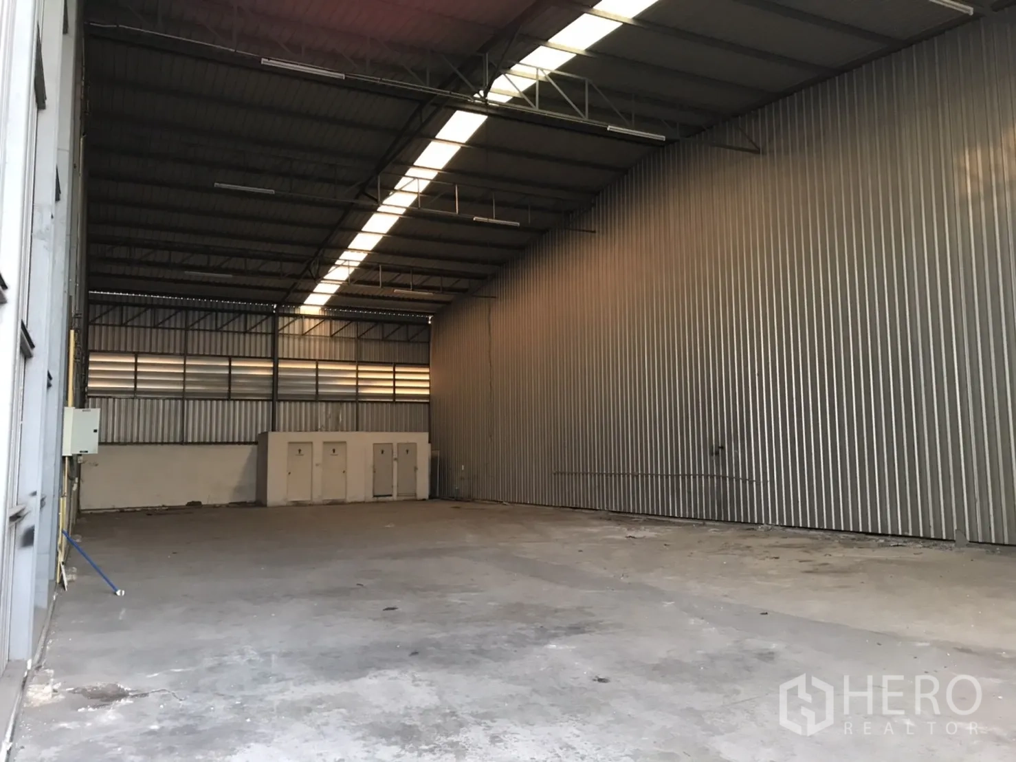 Warehouse for rent in Phra Pradaeng, Samut Prakan - Empty warehouse interior showing a high roof with skylights and a smooth concrete floor.