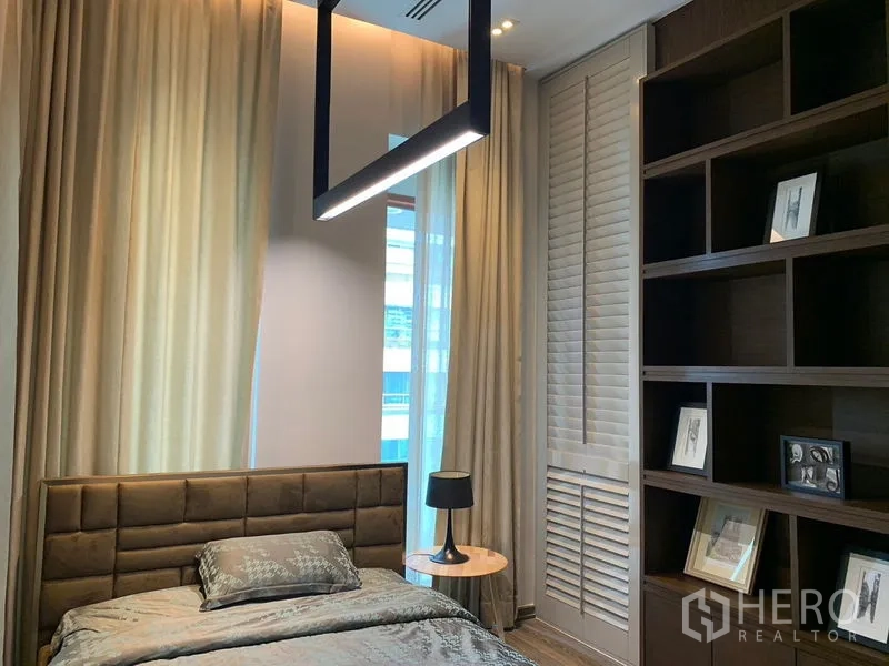 Condominium for rent - Cozy bedroom with single bed, tall bookshelves and full-height curtains.