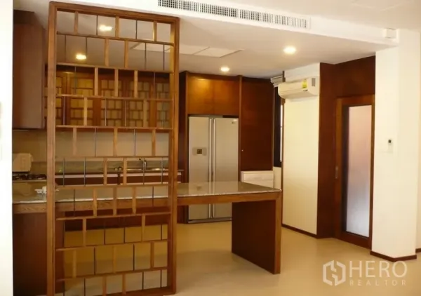 บ้าน ให้เช่าในKhlong Toei, Bangkok - ครัวโทนไม้พร้อมเคาน์เตอร์ทานอาหาร ชั้นกั้นแบบลายช่อง และตู้เย็นบานคู่