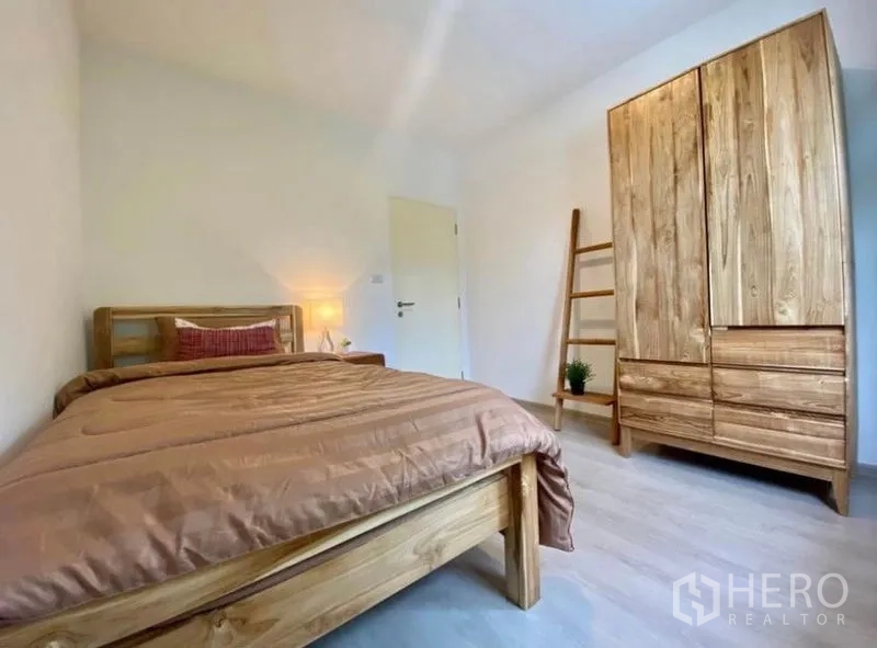 ทาวน์เฮาส์ ให้เช่าในBang Phli, Samut Prakan - ห้องนอนรองอบอุ่น เตียงไม้ ตู้เสื้อผ้าทรงสูง และบันไดวางของ