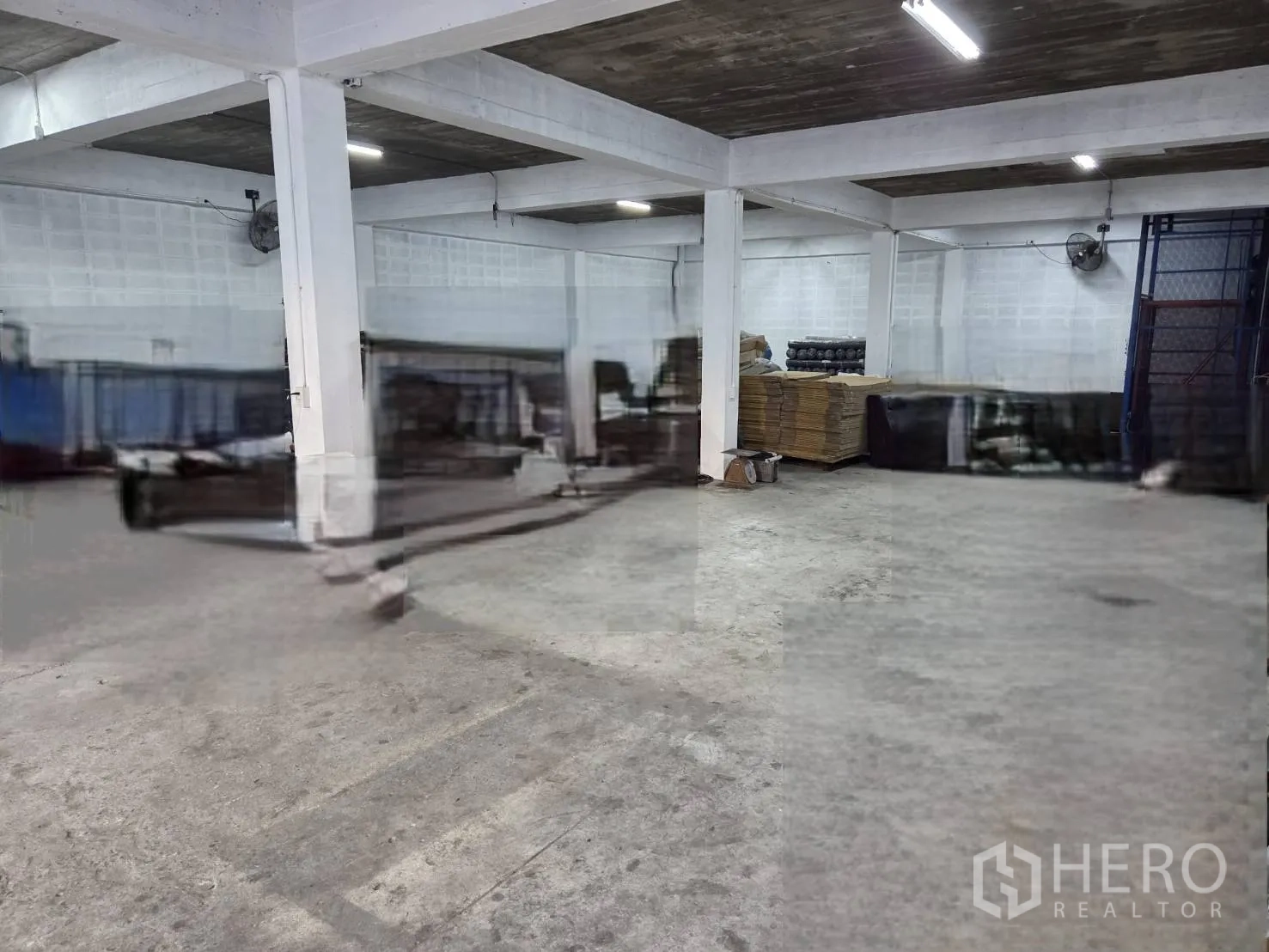 仓库 for rent in Ratchathewi, Bangkok - 一层开放空间，混凝土地面、结构柱、壁挂风扇与照明。