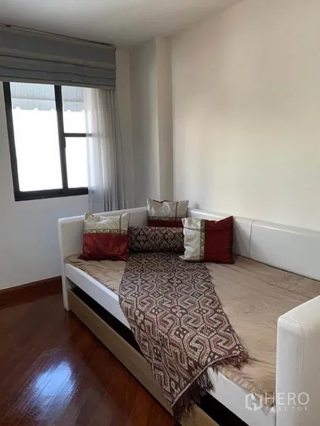 Townhouse for rent in Khlong Toei, Bangkok - Cozy secondary room with daybed by the window, sheer curtains and wood flooring.