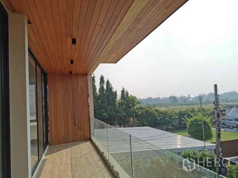 Detached House for rent in Bang Phli, Samut Prakan - Long balcony with glass railing and timber ceiling overlooking greenery
