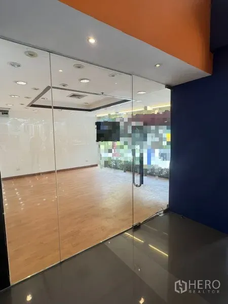 零售空间 出租在Pathum Wan, Bangkok - 玻璃入口门通向明亮的店铺空间，木地板与射灯。