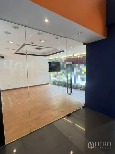零售空间 出租在Pathum Wan, Bangkok - 玻璃入口门通向明亮的店铺空间，木地板与射灯。