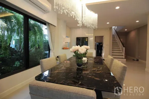 独立式住宅 出租在Prawet, Bangkok - 餐区配黑色大理石餐桌与水晶吊灯。