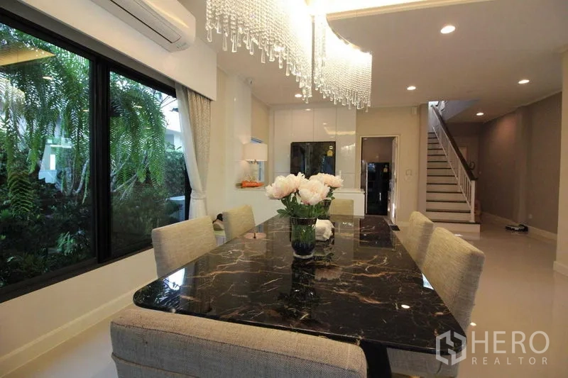 独立式住宅 出租在Prawet, Bangkok - 餐区配黑色大理石餐桌与水晶吊灯。