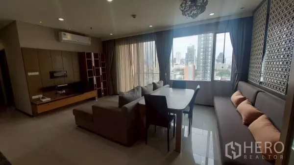 คอนโด ให้เช่าในKhlong San, Bangkok - พื้นที่นั่งเล่นและรับประทานอาหารแบบโอเพ่น พร้อมโซฟาเข้ามุม โต๊ะ และหน้าต่างบานกว้างมองเห็นวิวสกายไลน์กรุงเทพฯ