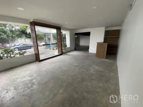 零售空间 出租在Bangkok - 明亮临街门面，整面玻璃入口与展示窗，开放式销售区混凝土地面。