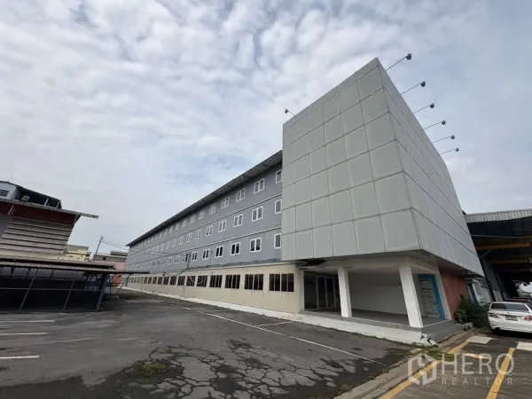 工厂 出租在Phra Pradaeng, Samut Prakan - 现代办公楼立面与仓库相连，车道与停车区宽敞。