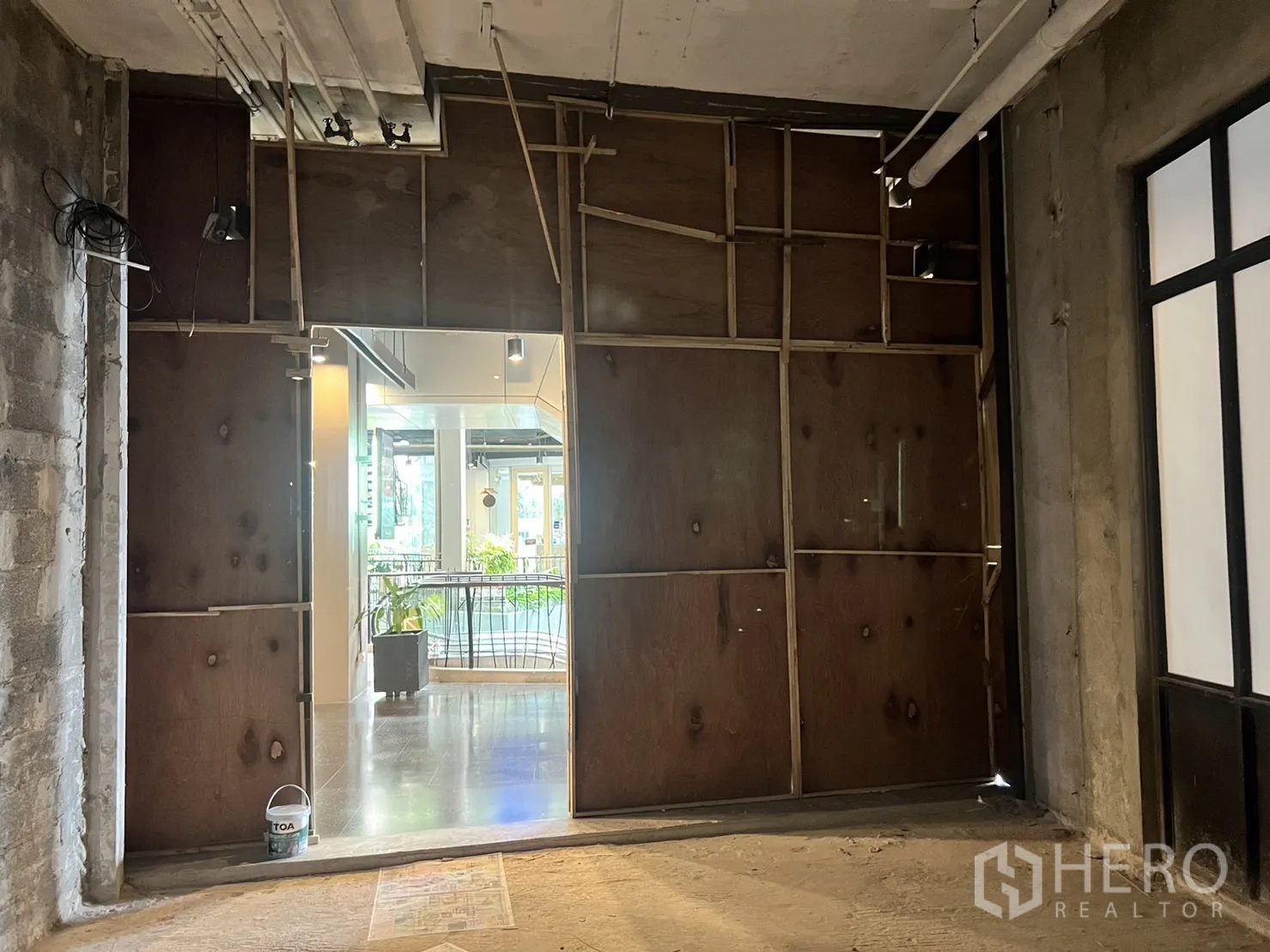 零售空间 出租在Khlong Toei, Bangkok - 店内以夹板封闭的临时门面，通向明亮的室内商场走廊