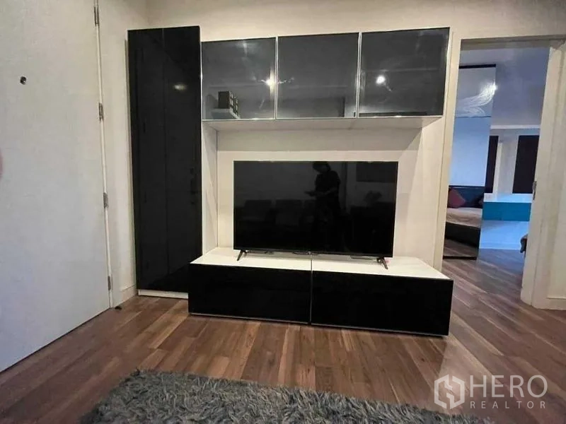 Condominium for sale - Living area with built-in black gloss TV cabinet and warm wood flooring.