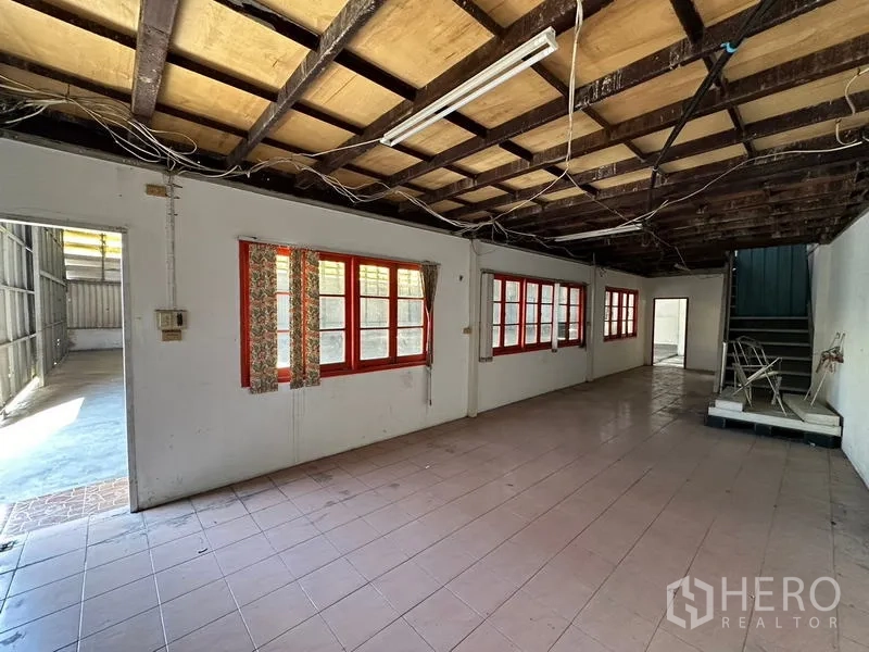 Warehouse for rent in Suan Luang, Bangkok - Basic office room with tiled floor, exposed timber ceiling and red-framed windows.