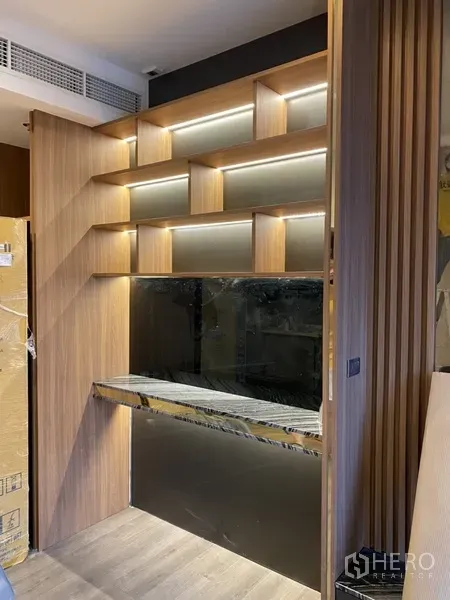 Condominium for sale in Phra Khanong, Bangkok - Built-in wooden shelving with LED lighting and a marble counter in a modern condo.