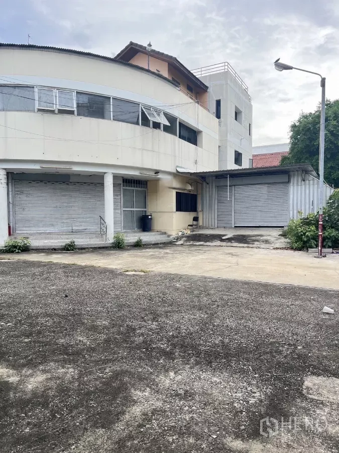 Warehouse for rent in Huai Khwang, Bangkok - Curved warehouse exterior in Huai Khwang with roller shutters and a wide loading yard.