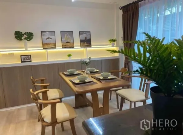 联排别墅 出租在Prawet, Bangkok - 四人餐区，暖色背光展示架与纱帘。