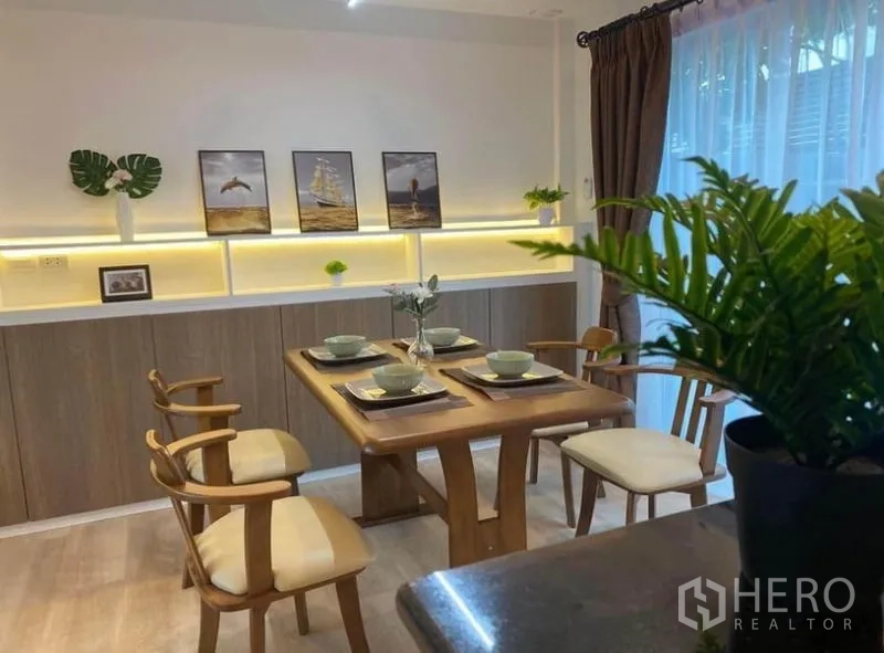 联排别墅 出租在Prawet, Bangkok - 四人餐区，暖色背光展示架与纱帘。