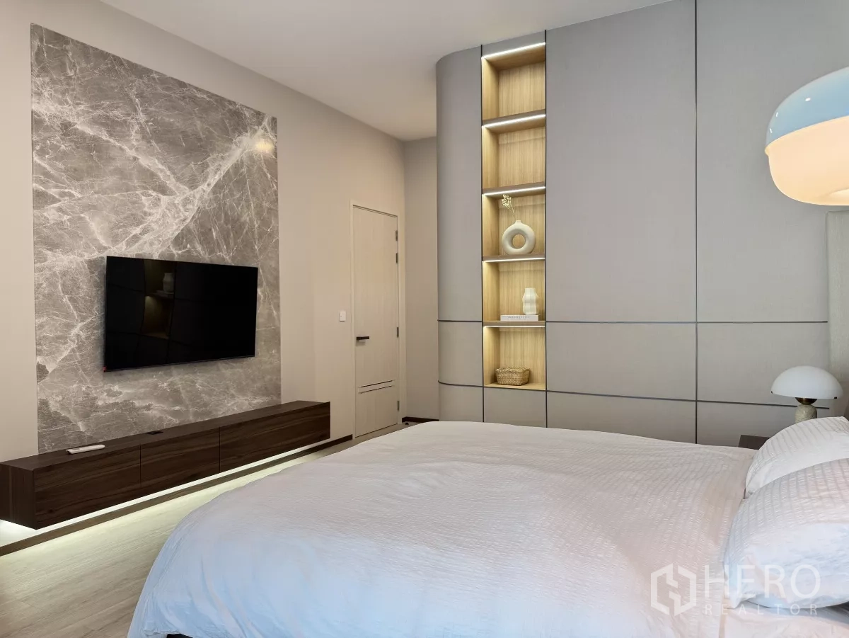 Detached House for rent in Saphan Sung, Bangkok - Bedroom media wall featuring a mounted TV, marble slab feature and illuminated display shelves.